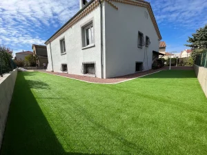 Contour de maison en gazon synthétique et gravier stabilisé